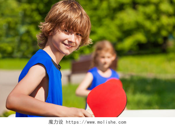 男孩和女孩在一起打乒乓球在夏天阳光灿烂的日子